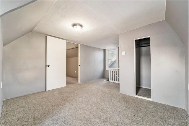 additional living space with carpet flooring, a textured ceiling, and vaulted ceiling