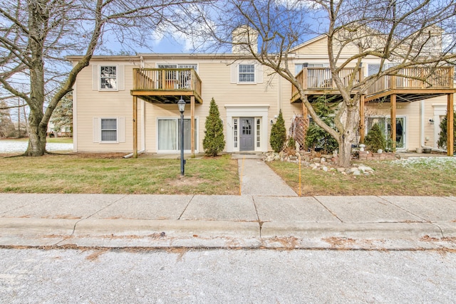 view of front of home featuring a front yard, a wooden deck, and a balcony