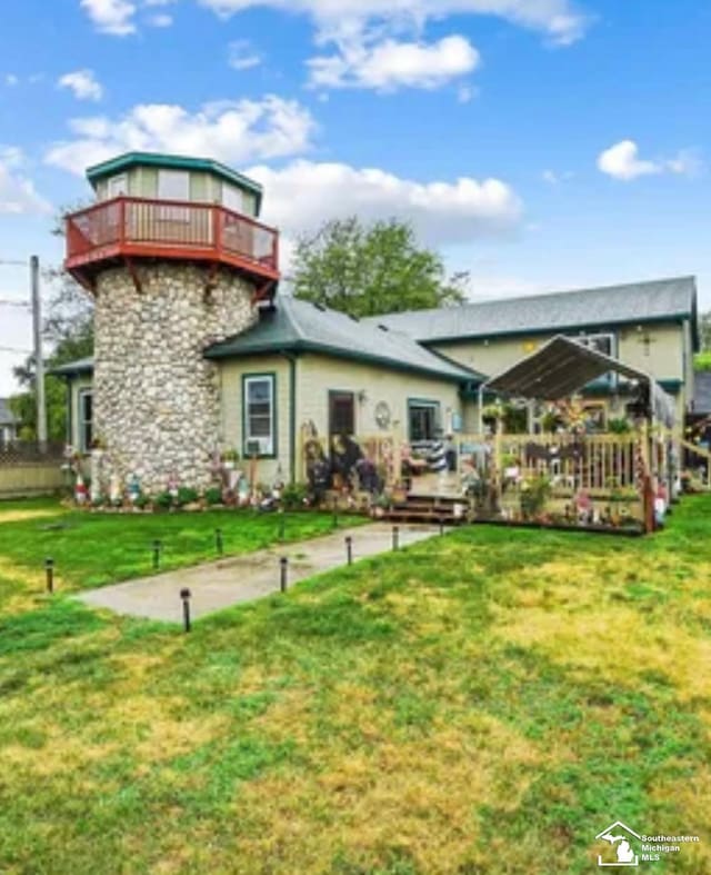 back of property featuring a yard, a balcony, and a deck