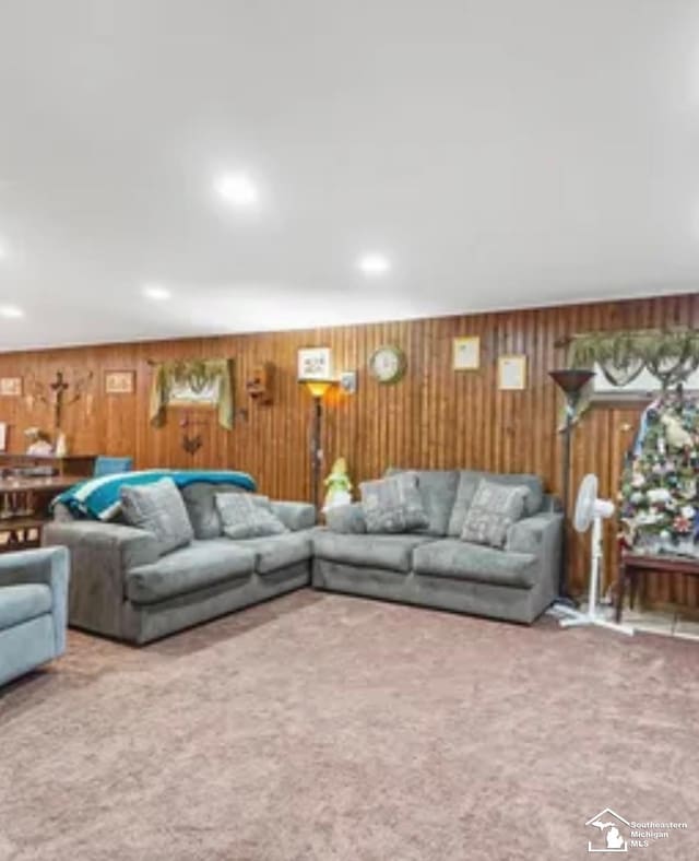 carpeted living room with wood walls