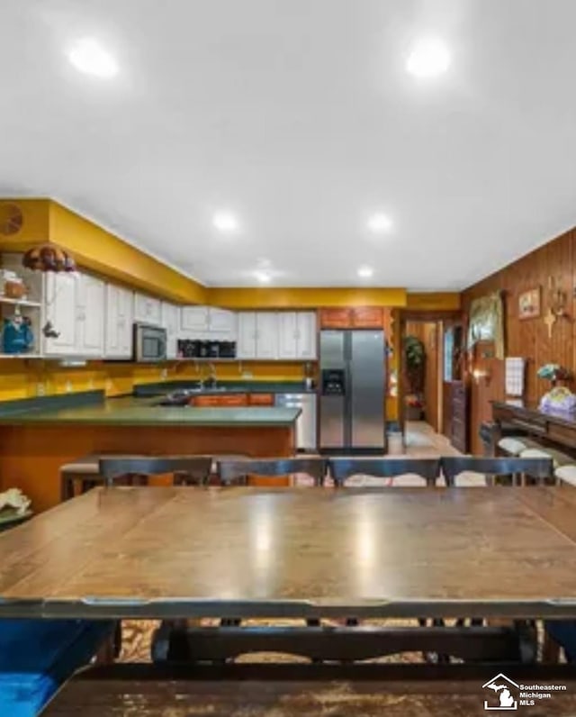 kitchen featuring white cabinets, stainless steel refrigerator with ice dispenser, and a kitchen breakfast bar