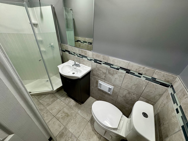 bathroom with a shower with door, vanity, tile walls, and toilet