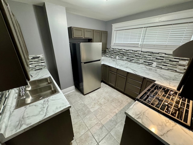 kitchen with backsplash, stainless steel refrigerator, and sink