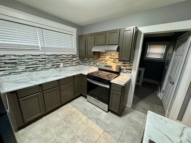 kitchen with backsplash, stainless steel range with gas cooktop, and light stone counters