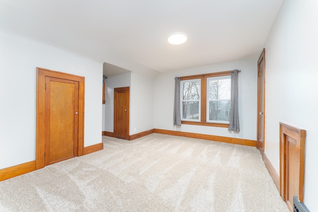 spare room with light colored carpet and a baseboard heating unit