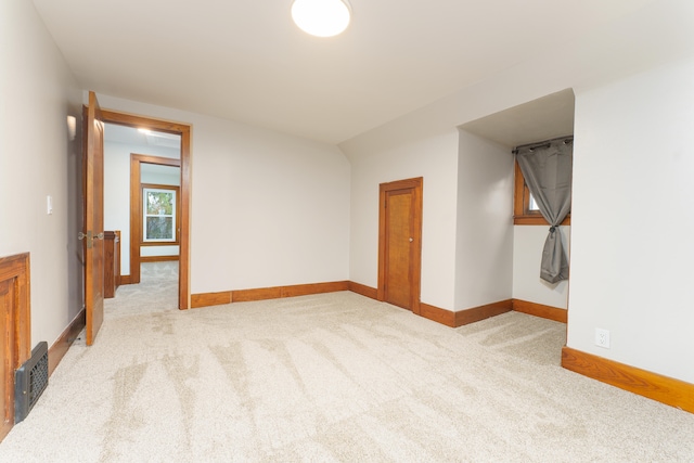empty room featuring light carpet and vaulted ceiling