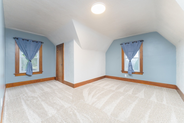 bonus room featuring a healthy amount of sunlight, carpet floors, a textured ceiling, and vaulted ceiling