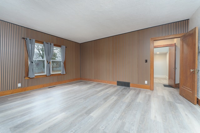 unfurnished room with a textured ceiling and light wood-type flooring