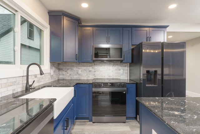 kitchen featuring decorative backsplash, light hardwood / wood-style floors, dark stone countertops, and stainless steel appliances