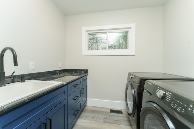 washroom with washer and dryer, light hardwood / wood-style floors, cabinets, and sink