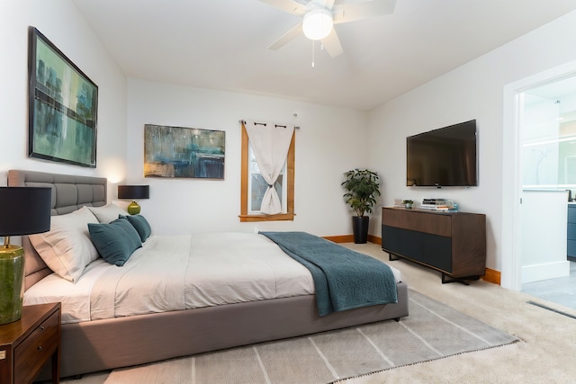 bedroom with ceiling fan, ensuite bathroom, and light carpet