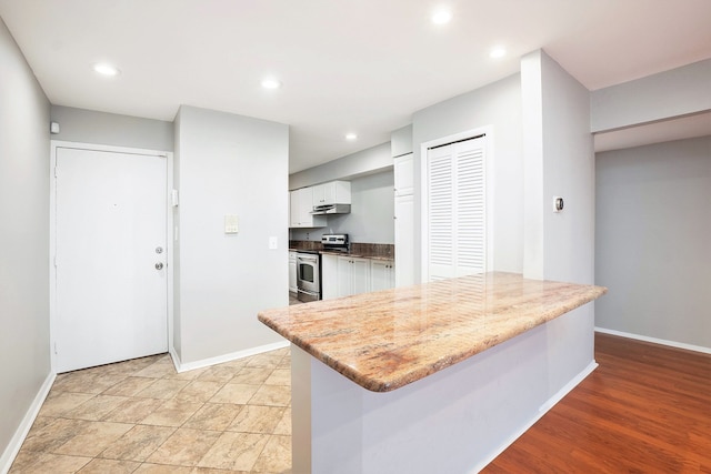 kitchen with light wood-type flooring, light stone counters, a kitchen island, white cabinets, and stainless steel electric range oven