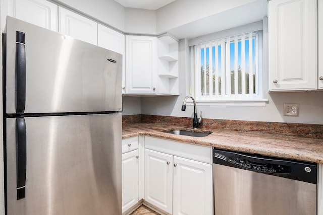 kitchen with dark stone countertops, white cabinetry, sink, and appliances with stainless steel finishes