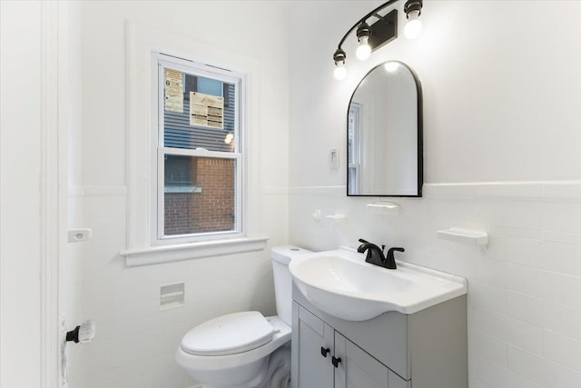 bathroom with vanity, toilet, and tile walls