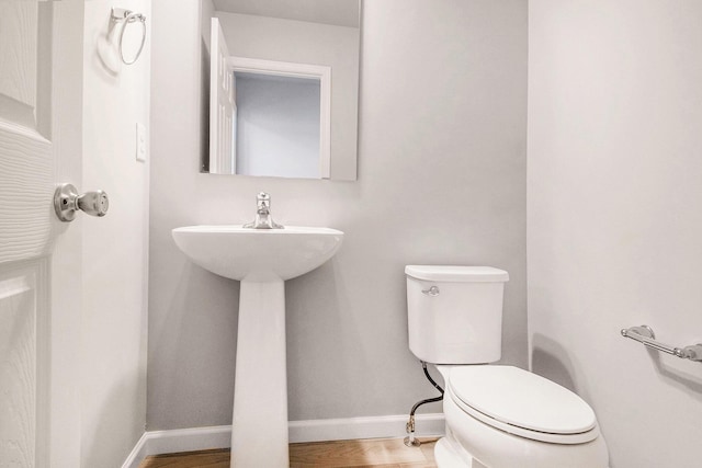 half bathroom featuring toilet and baseboards