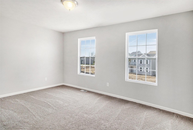 carpeted spare room with visible vents and baseboards