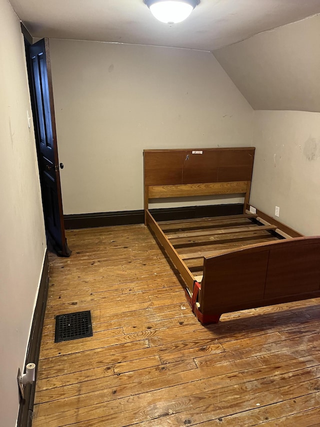 unfurnished bedroom with lofted ceiling and wood-type flooring