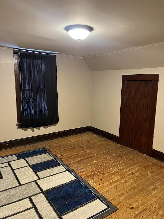 empty room featuring hardwood / wood-style floors and vaulted ceiling