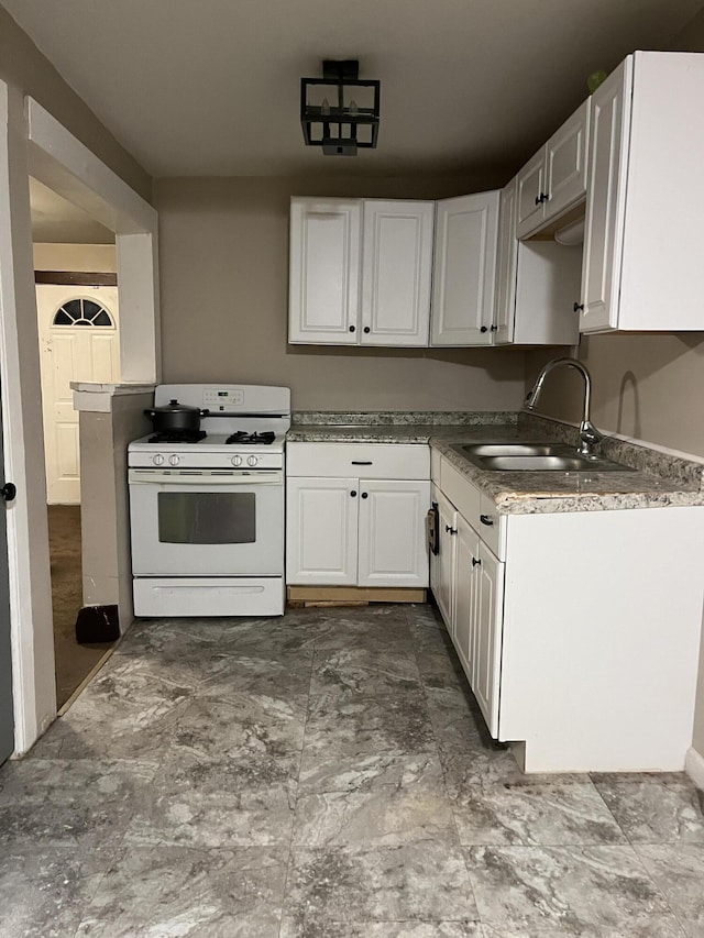 kitchen with white range with gas cooktop, white cabinetry, and a sink