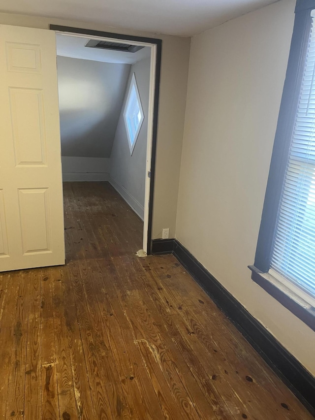 additional living space with dark wood-style floors, plenty of natural light, lofted ceiling, and baseboards