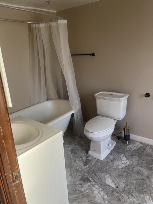 bathroom featuring marble finish floor, toilet, vanity, a shower with curtain, and baseboards