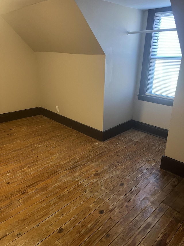 additional living space with lofted ceiling, baseboards, and dark wood-type flooring