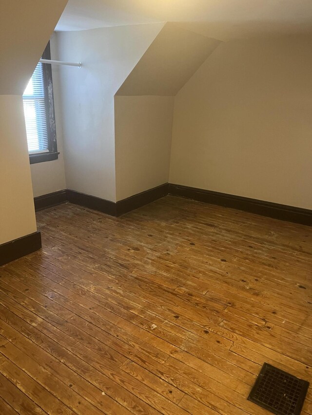 additional living space with lofted ceiling, hardwood / wood-style floors, and baseboards