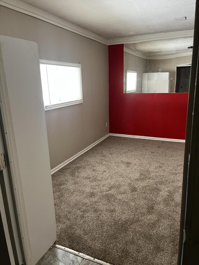 empty room with carpet, plenty of natural light, baseboards, and crown molding