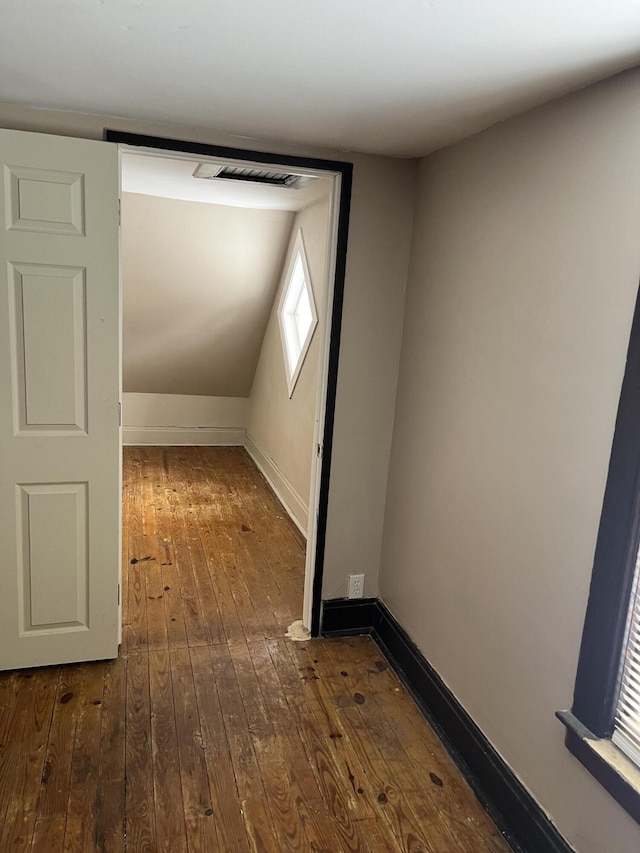 additional living space with dark wood-style flooring, visible vents, and baseboards