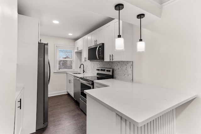 kitchen featuring kitchen peninsula, dark hardwood / wood-style flooring, stainless steel appliances, sink, and white cabinets