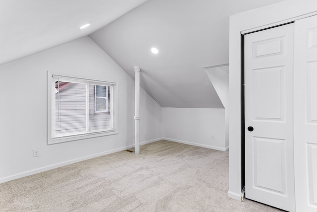 additional living space with light colored carpet and lofted ceiling