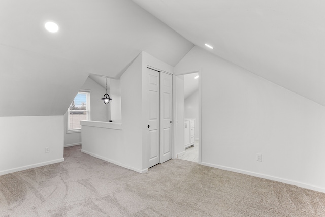 additional living space featuring light colored carpet and vaulted ceiling