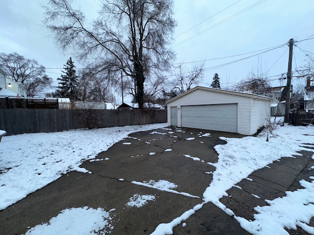 snowy yard with a garage and an outdoor structure