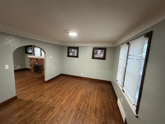 spare room featuring dark hardwood / wood-style flooring, a fireplace, and ornamental molding