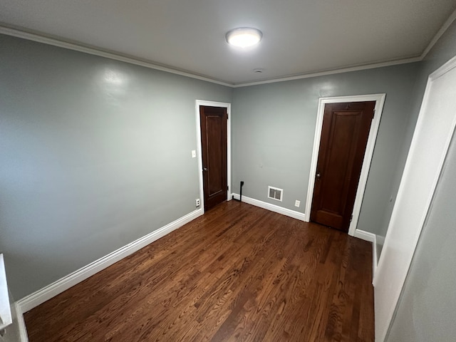 unfurnished bedroom with dark hardwood / wood-style flooring and crown molding