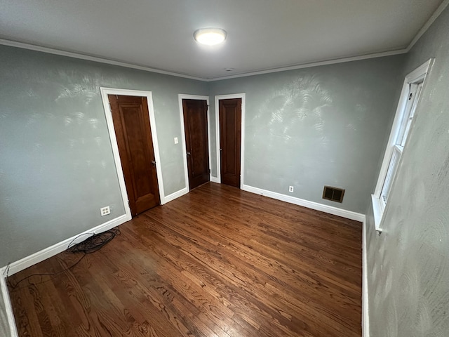 unfurnished bedroom featuring crown molding and dark wood-type flooring