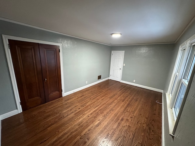 unfurnished bedroom with crown molding, a closet, and dark wood-type flooring