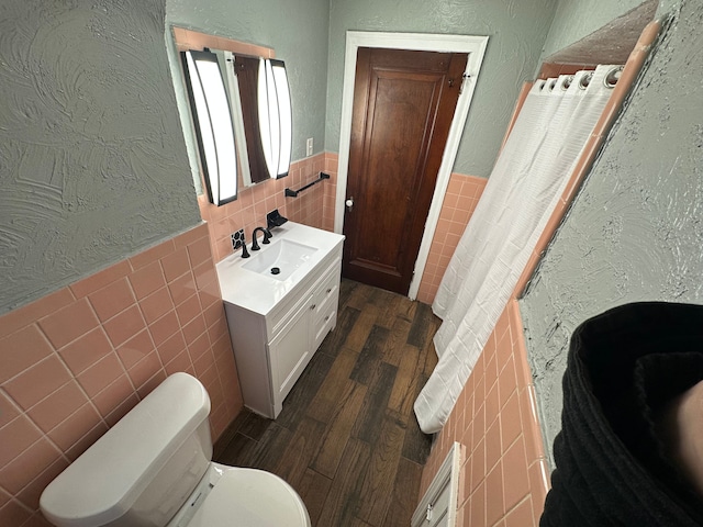 bathroom featuring vanity, toilet, wood-type flooring, and tile walls