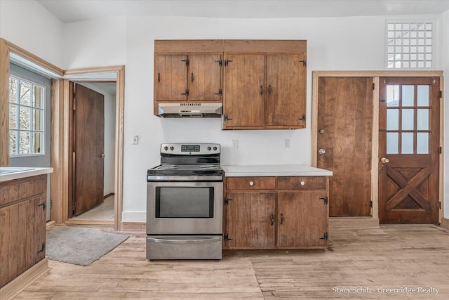 kitchen featuring stainless steel electric stove and light hardwood / wood-style flooring