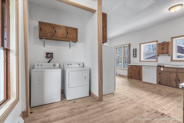 clothes washing area with washer and clothes dryer and light hardwood / wood-style floors