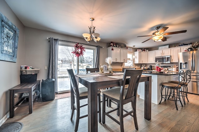 dining area featuring ceiling fan with notable chandelier and light wood-type flooring