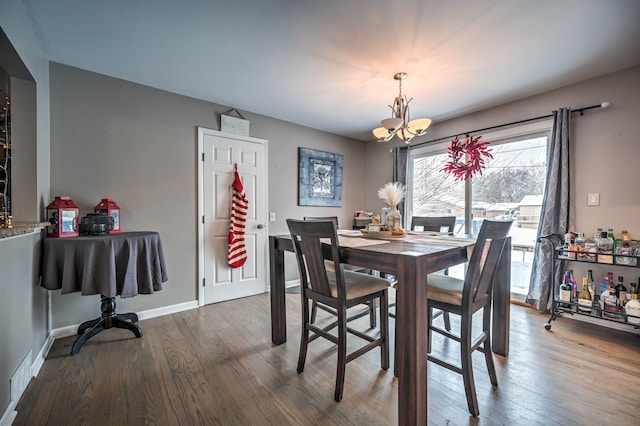 dining space with hardwood / wood-style floors and an inviting chandelier