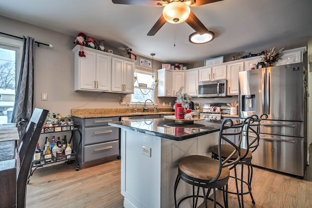 kitchen with a center island, stainless steel appliances, white cabinetry, and dark stone counters