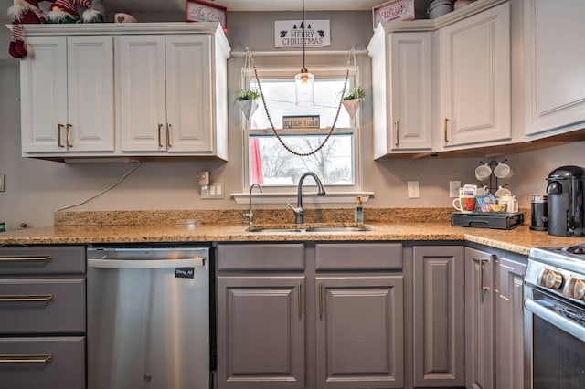 kitchen featuring white cabinets, sink, hanging light fixtures, light stone countertops, and stainless steel appliances