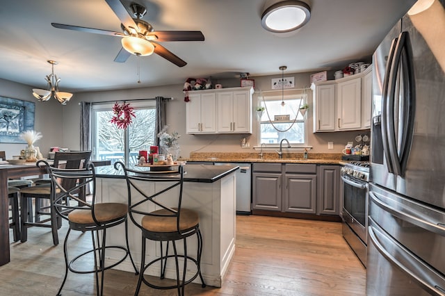 kitchen with white cabinets, decorative light fixtures, stainless steel appliances, and a breakfast bar