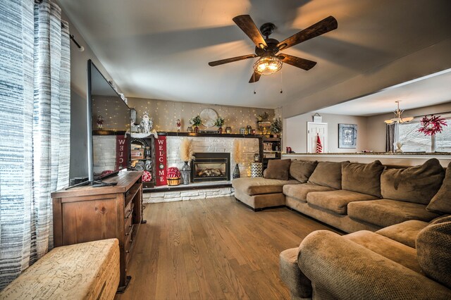 living room featuring hardwood / wood-style floors, ceiling fan, and a stone fireplace