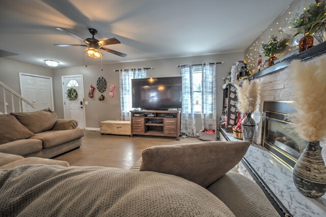 living room with hardwood / wood-style flooring, ceiling fan, and a high end fireplace