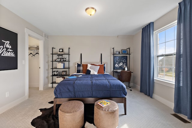 bedroom with multiple windows, a walk in closet, a closet, and light colored carpet