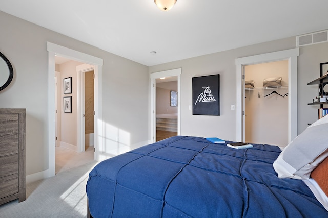 bedroom with a walk in closet, light carpet, and a closet