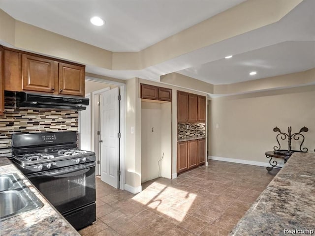 kitchen featuring sink, decorative backsplash, black gas stove, and light stone counters